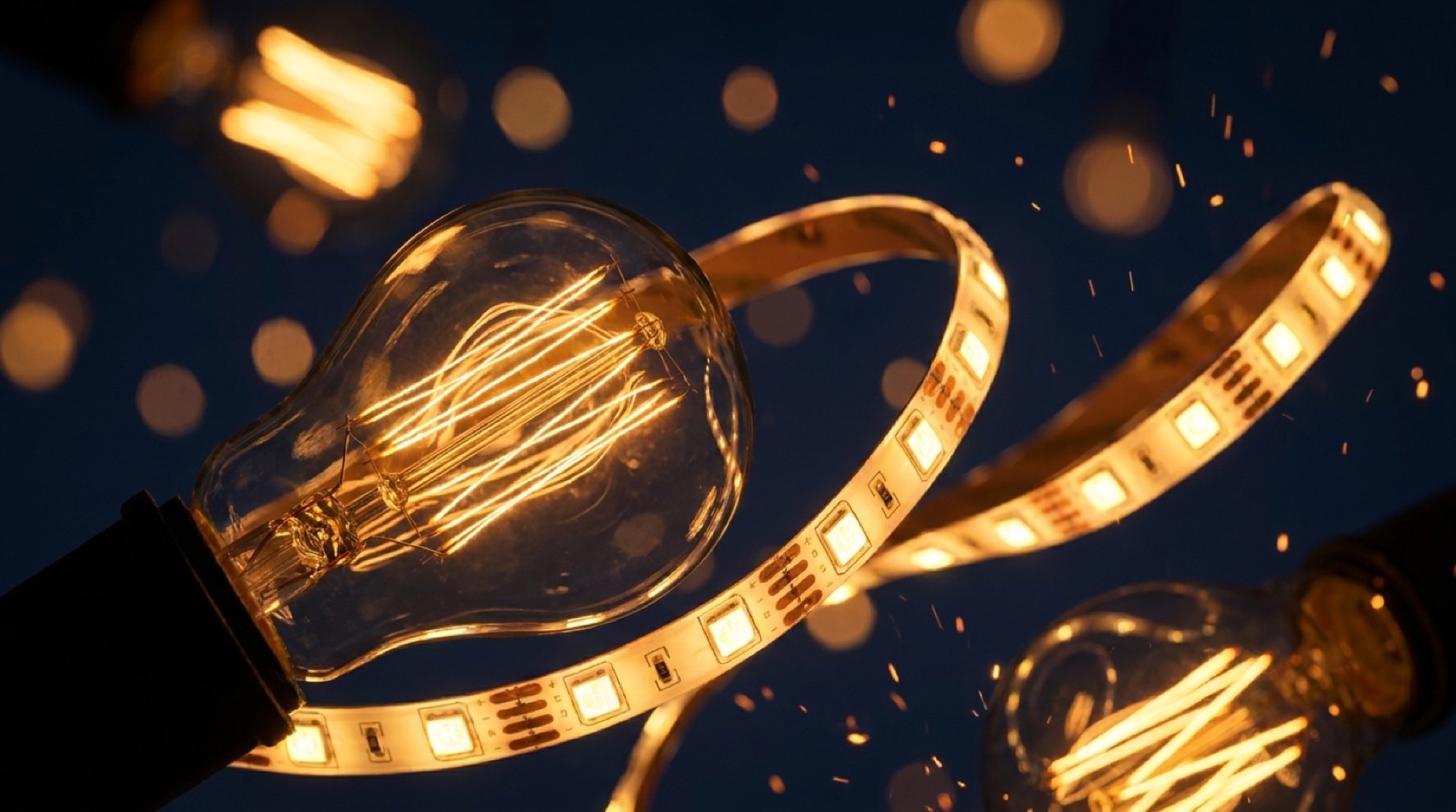 Filament bulbs and a lit LED strip glowing against a dark blue background