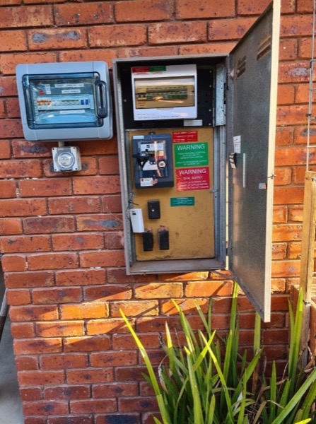 A meter box and switchboard mounted on the brick wall of a house
