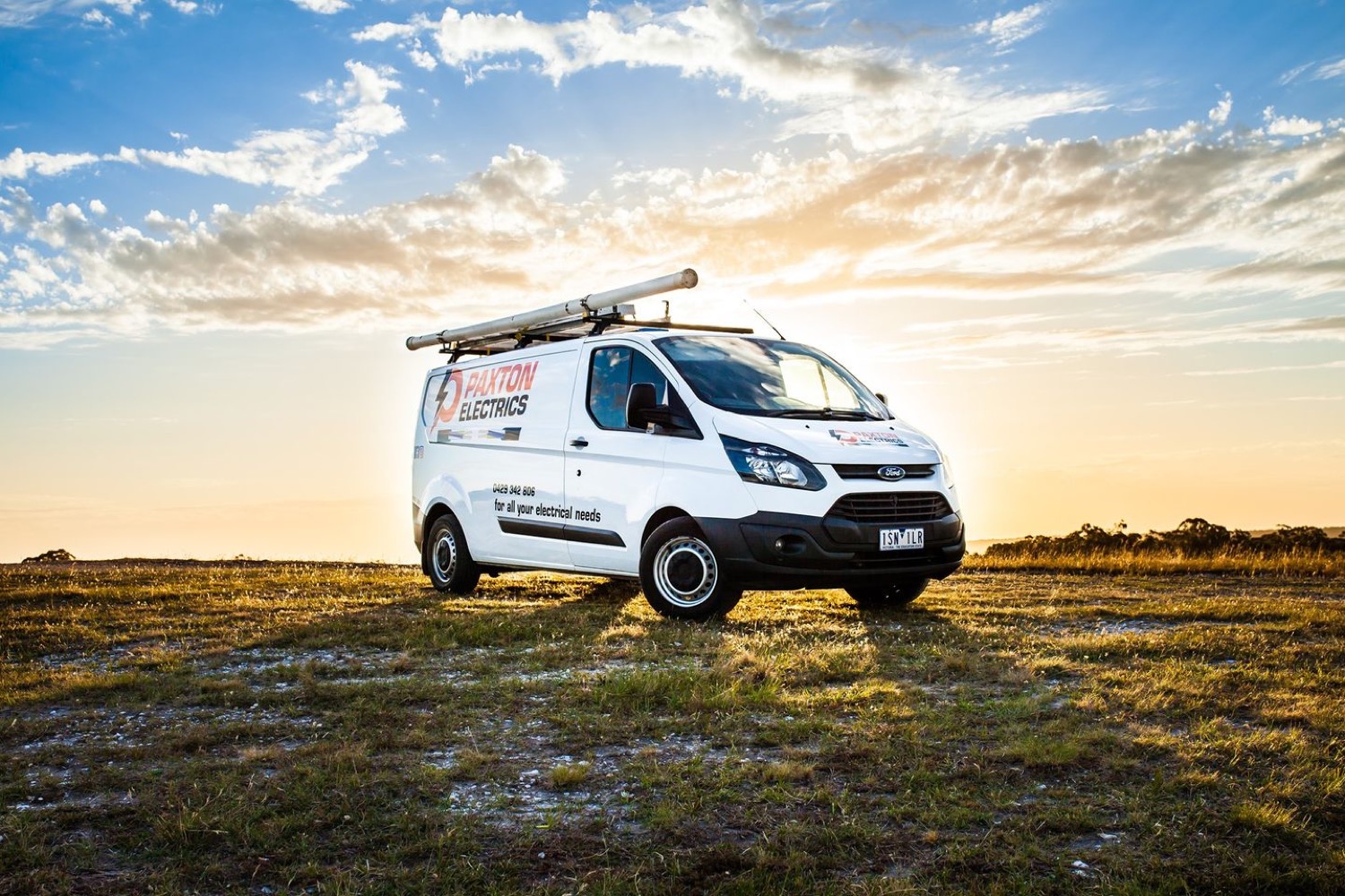 The Paxton Electrics van parked in a paddock with a ladder on the roof rack at sunset