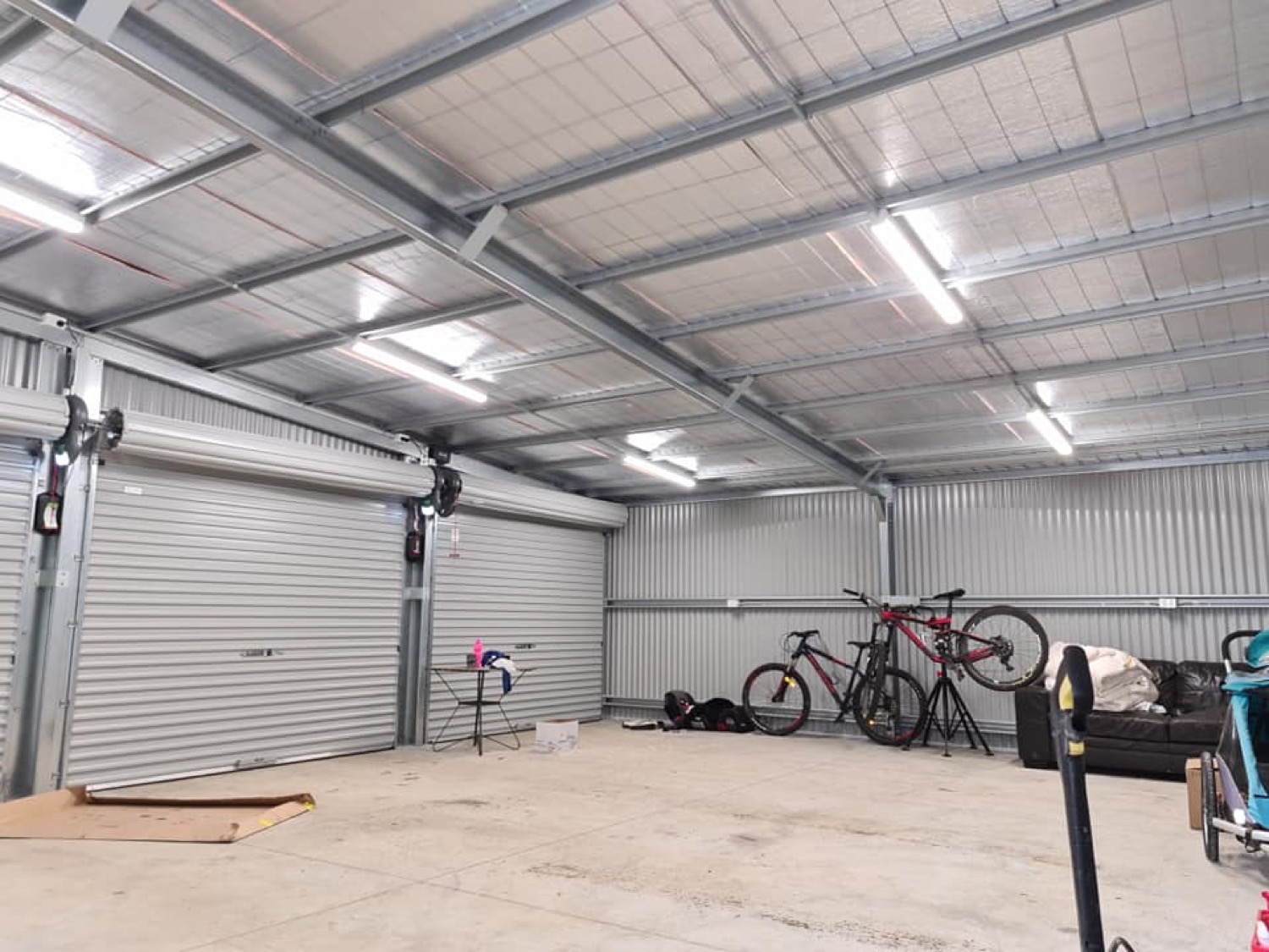 The inside of a large shed with batten lights fitted along the roof frame