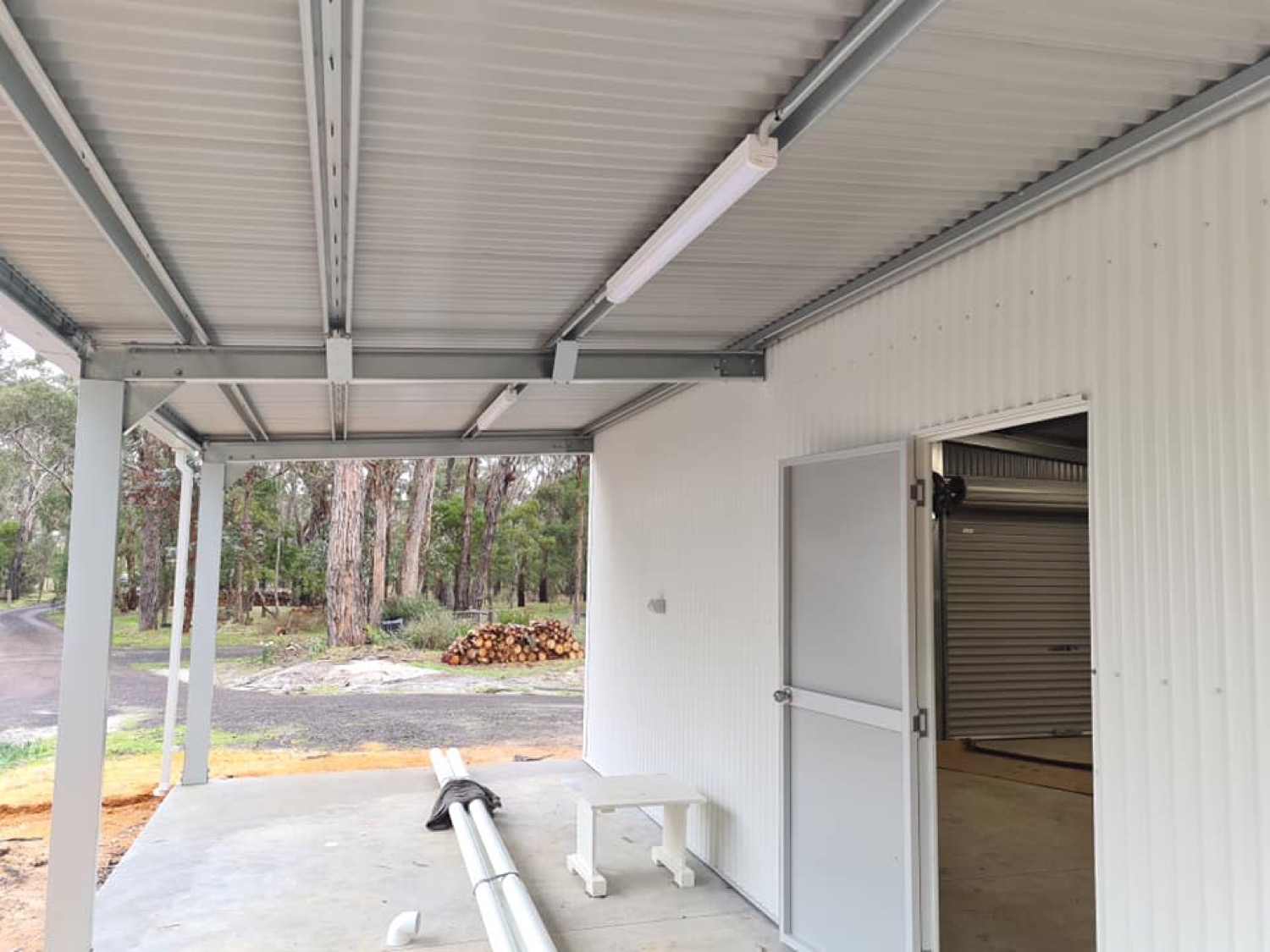 Batten lights fitted along the roof frame of a carport with the bushland visible beyond