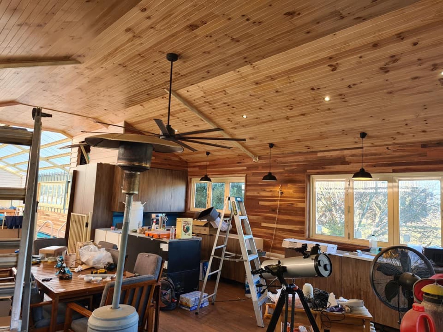 A timber-lined room with ceiling fans and pendant lights fitted overhead
